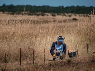 Man in a HALO visor and vest clearing mines in a field in Angola